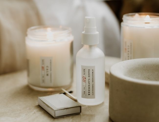 Atmosphere Threesixty Aromatherapy Candles and Aura Mist sitting on a bedside table with matches.